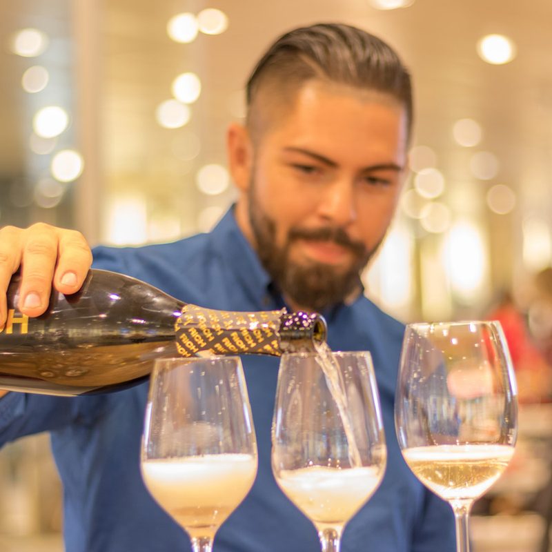 Man pouring three glasses of champagne.