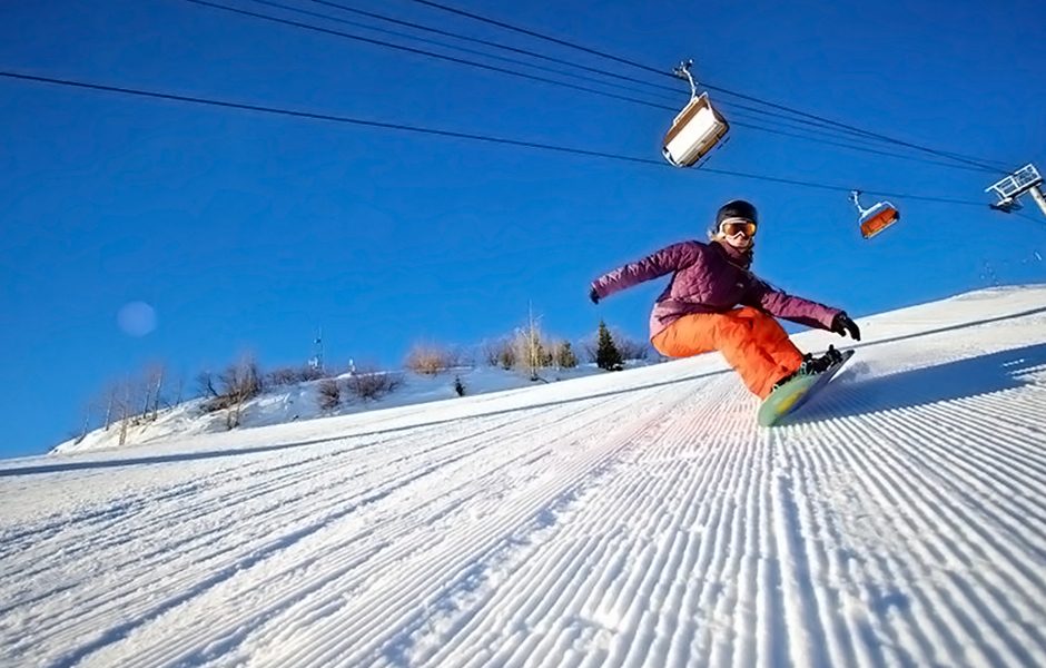 Low-angle shot of a snowboarder coming down a hill