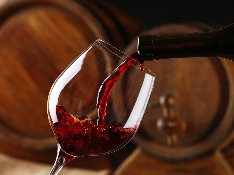 Pouring red wines with barrels in the background