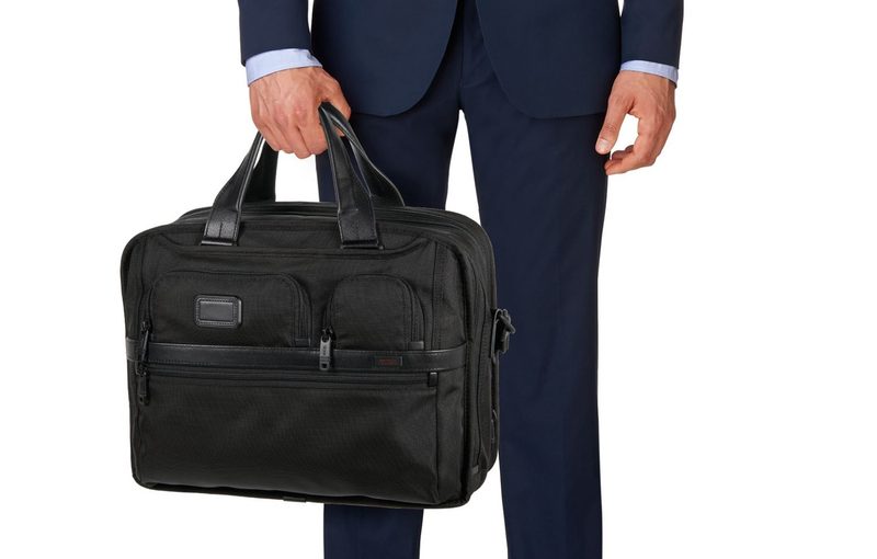 Holding a Tumi bag.