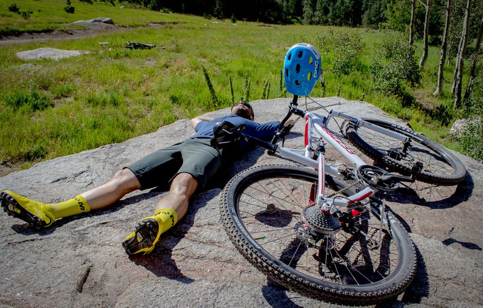 Man lays on the ground next to his bike.