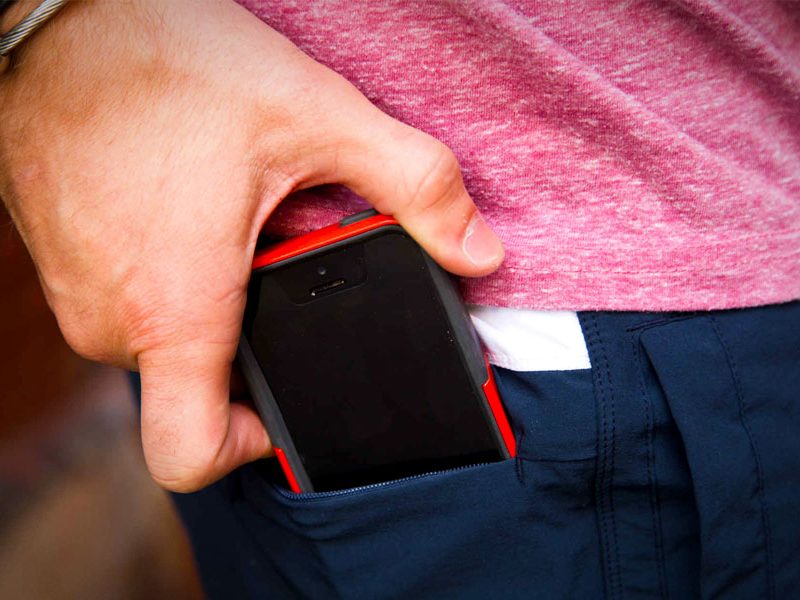 A person putting an iPhone into their pocket