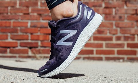 A New Balance shoe walking on the sidewalk.