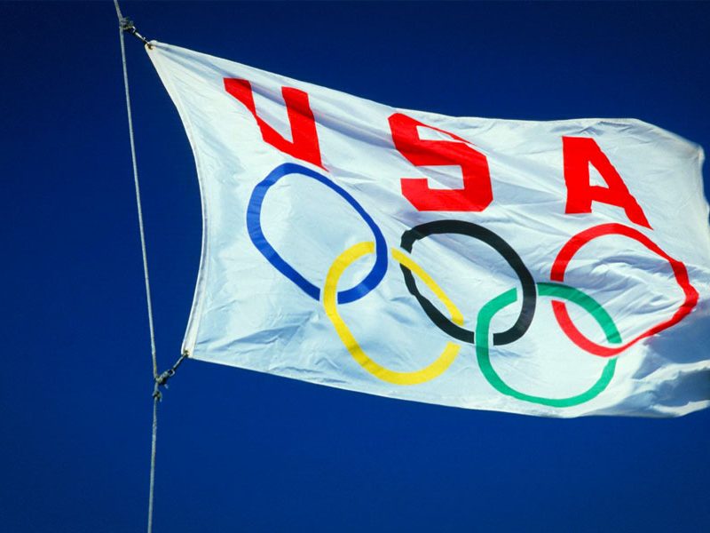 The USA Olympic flag flying against a blue sky.