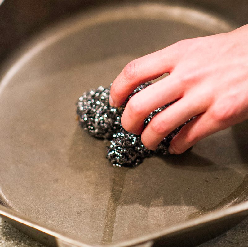Person cleaning a cast iron pan.
