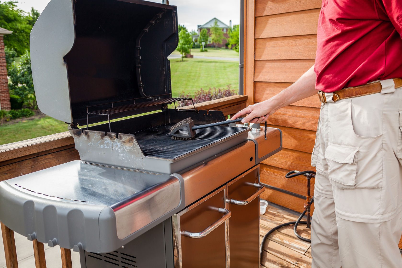 A man cleaning grill grates with a wire brush.