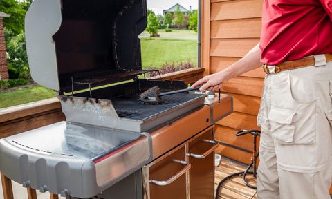 A man cleaning grill grates with a wire brush.