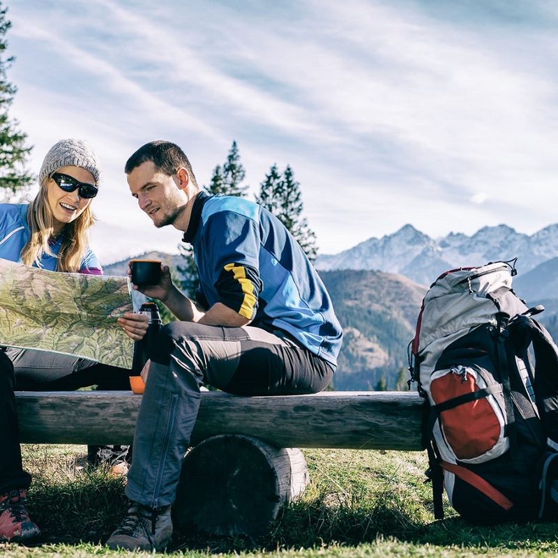 A couple sit on a bench and read a topographic map.