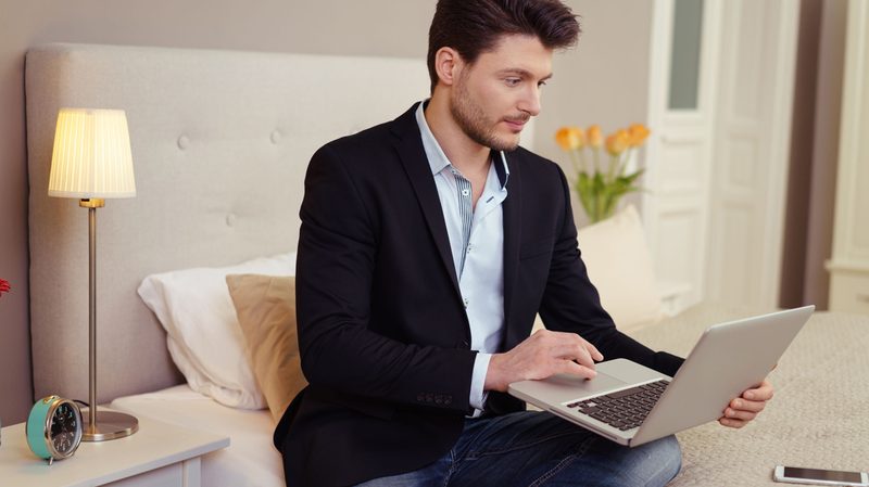 stock-man-using-laptop-on-bed-in-hotel