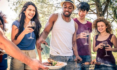 Friends enjoying grilled food and red wine.