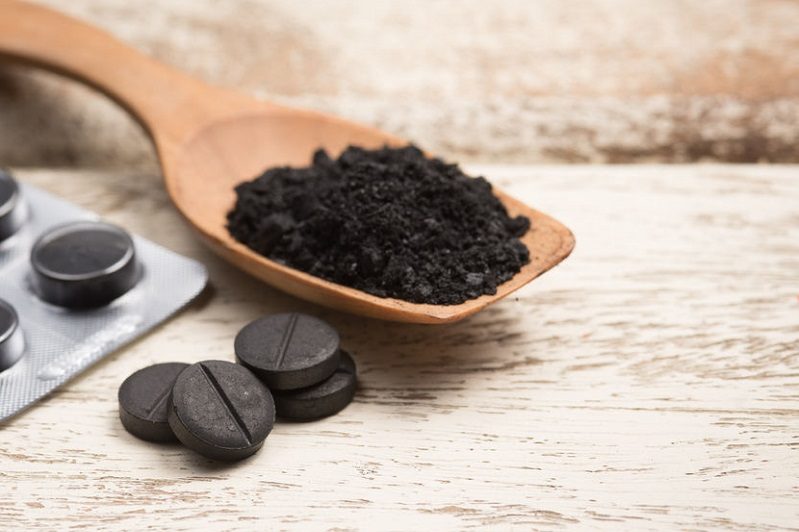 activated charcoal pellet and powder on wooden scoop, charcoal cocktails