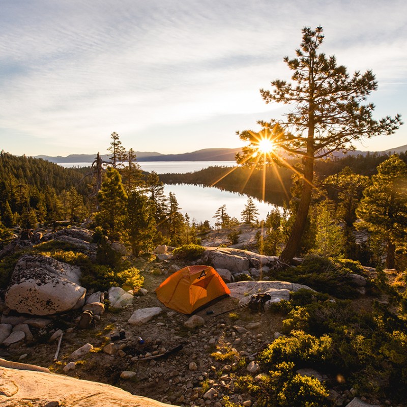 Mountain and lake landscape with sun overhead.