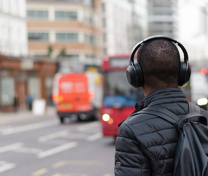 A man listening to a podcast while waiting for public vehicle.