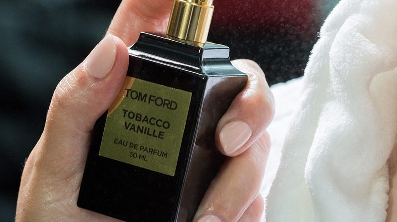 Someone spraying a Tom Ford cologne on themselves.