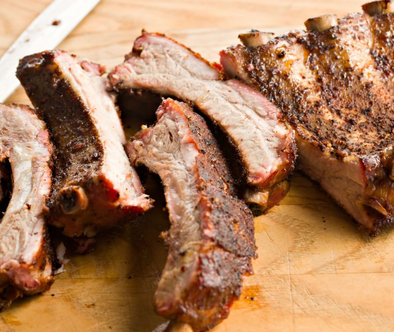 Deliciously smoked ribs chopped finely in a wooden cutting board.