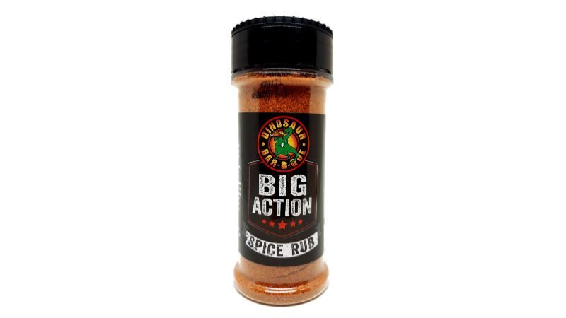 Dinosaur Bar-B-Que Big Action Spice Rub features a black label on its 5.5 oz. bottle, packed with sweet, savory, and spicy flavors.
