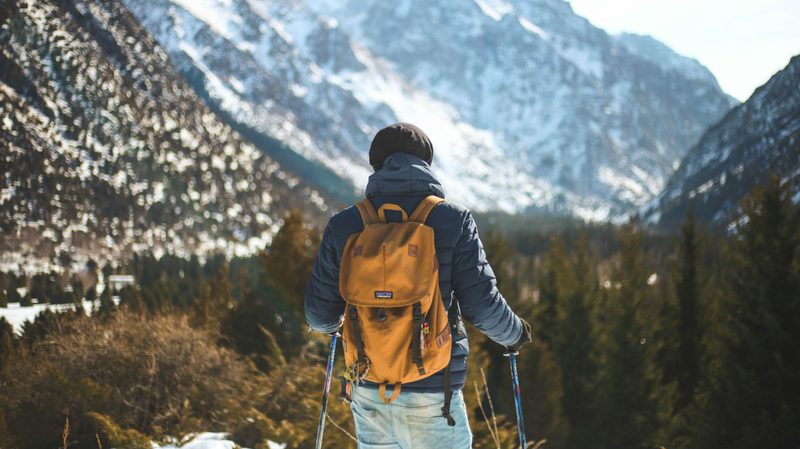 Man hiking with poles near a mountain