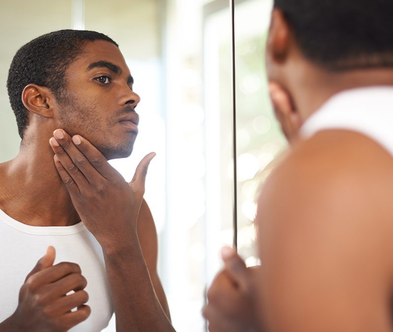 Man looking at skin in mirror