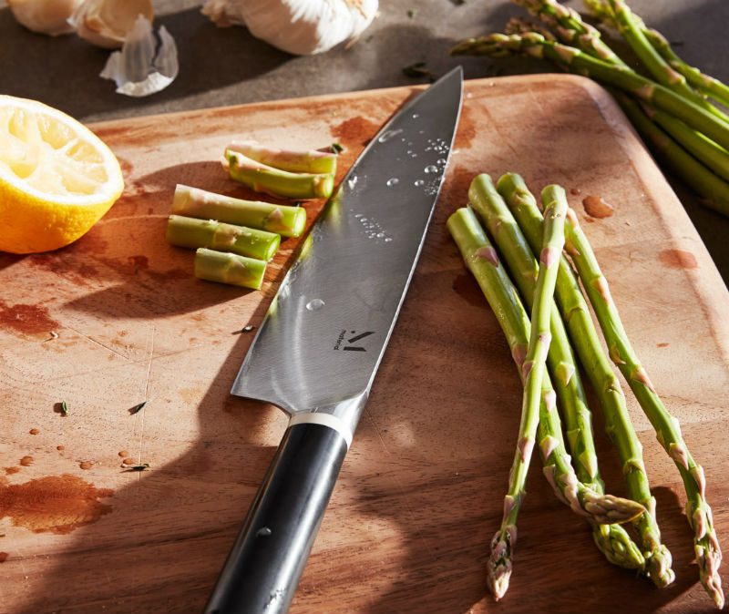Chopped lemon and asparagus on a chopping board with a knife.