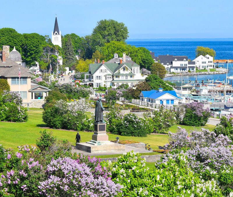 View of buildings amid flowers and greenery on the water on Michigan's Mackinac Island.