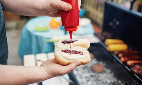 Man putting ketchup on a hot dog