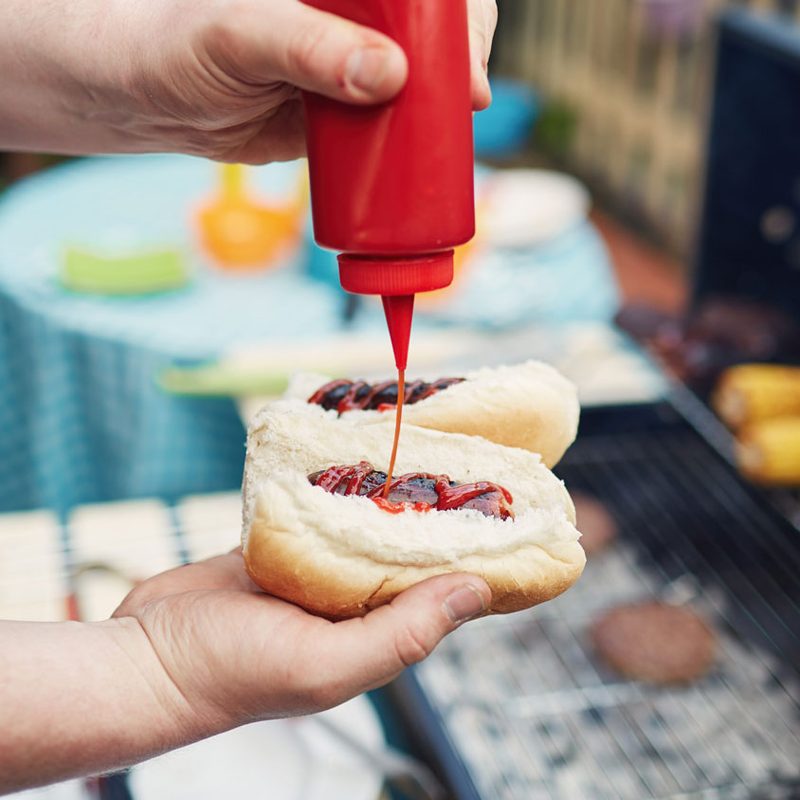 Man putting ketchup on a hot dog