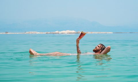 man reading a book while swimming