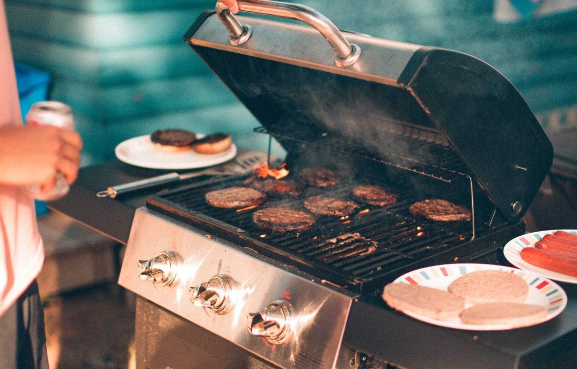 Man using a gas grill in his backyard