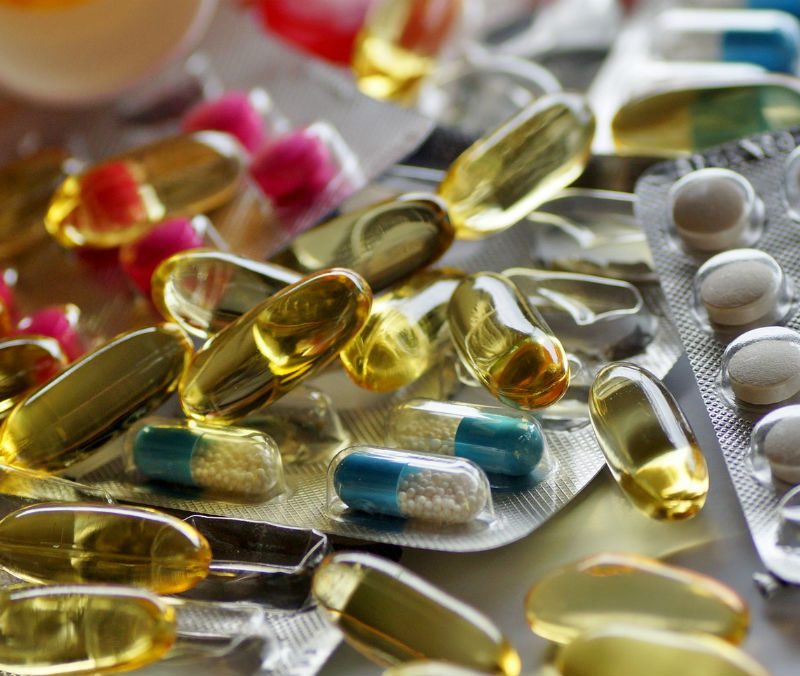 A pile of assorted pills and capsules in foil blister packs.