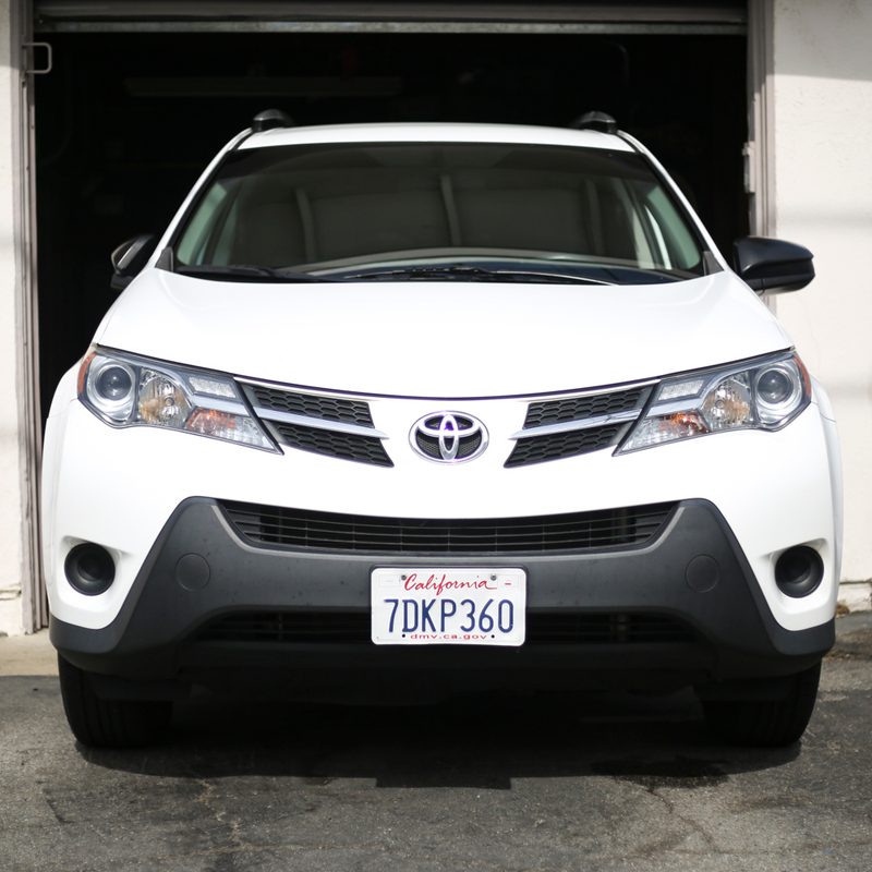 White Toyota RAV4 close up of front end in driveway.