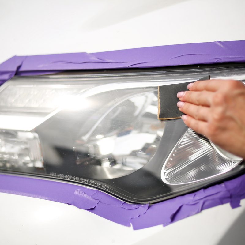 Man wiping alochol on Toyota RAV4 front headlight.