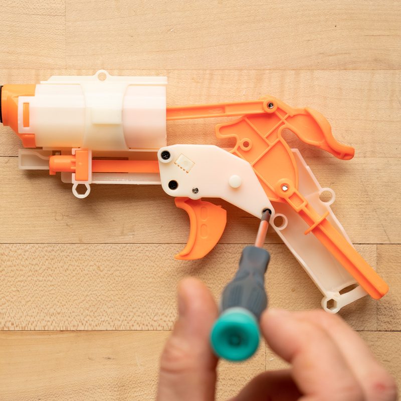 A hand holds a screwdriver to remove the screws.