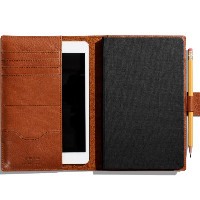 The Shinola Journal Cover containing an iPad, black journal, and pencil.