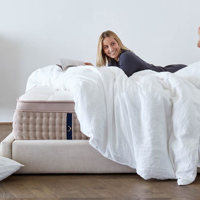 woman smiling atop dreamcloud mattress.