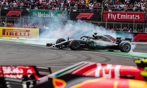 Formula 1 race cars rounding a corner.