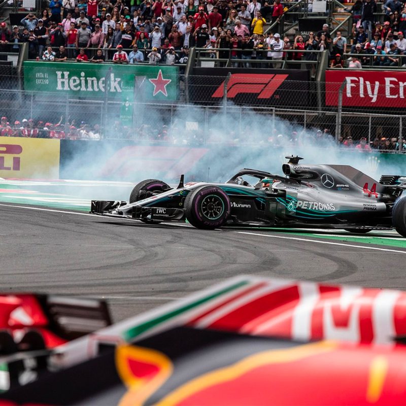 Formula 1 race cars rounding a corner.