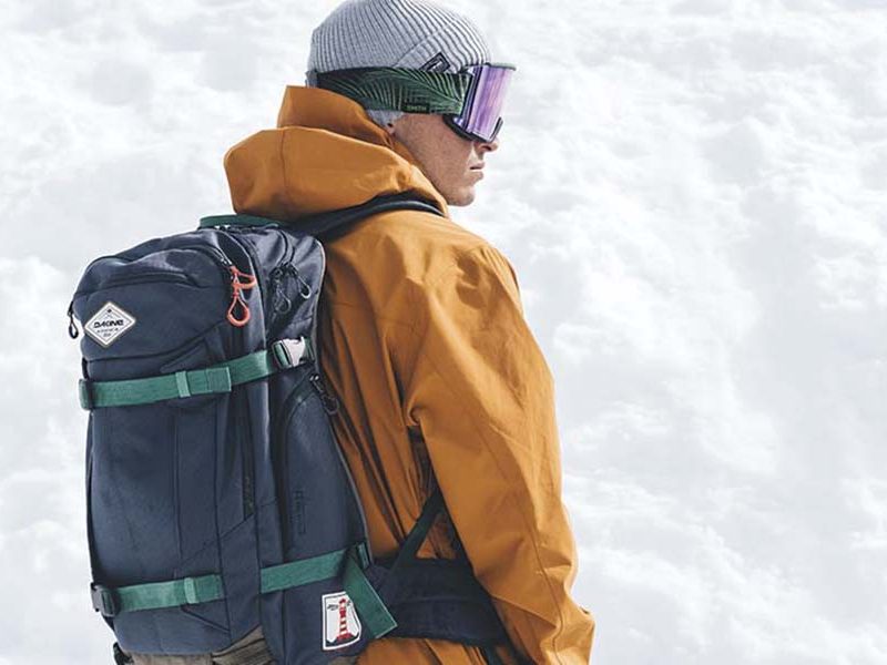 Snowboarding man wearing a Dakine Team Mission Pro 32L Backpack.