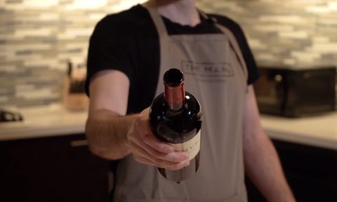 Person holding an open wine bottle toward the camera