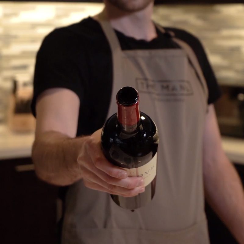 Person holding an open wine bottle toward the camera