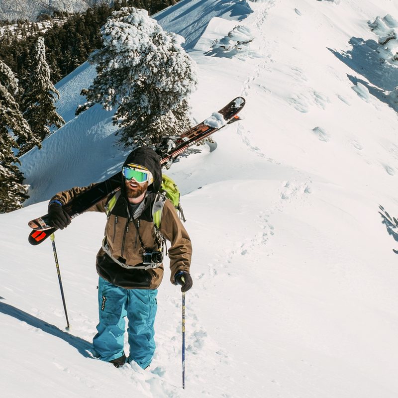 Man trekking skis up a snowy hill.