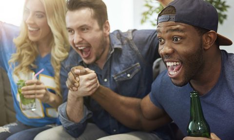 A group of friends cheering while watching a football game