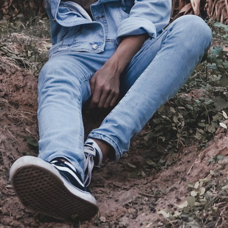 Man dressed in denim sitting on the ground.