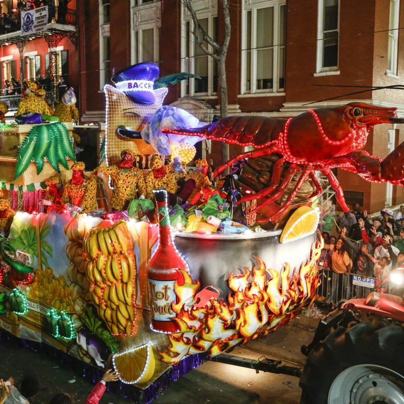 A tractor hauling a float with a huge lobster on the street at night.