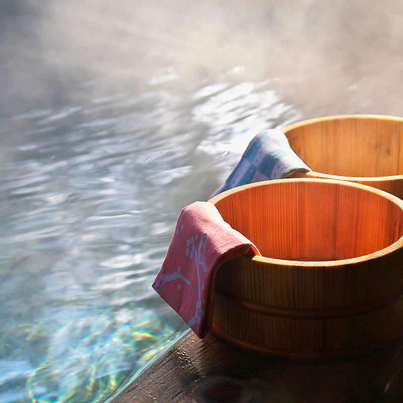 Two towel buckets draped with towels on the side of a Japanese onsen