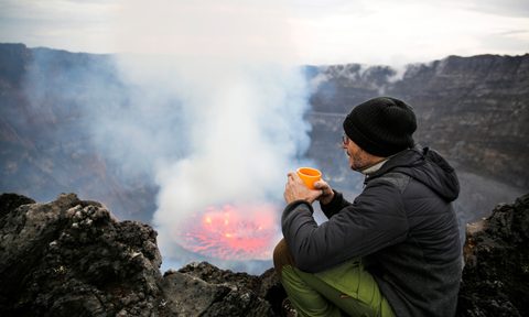virunga national park congo africa reopens sustainable travel  man sittiing over nyiragongo volcano crater getty images