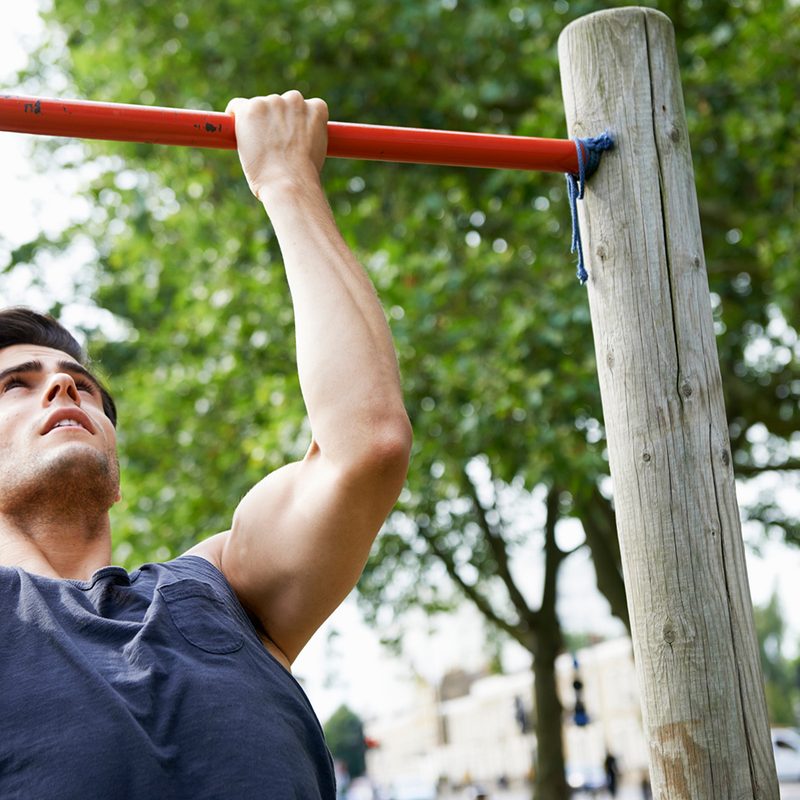 Man outside doing chin ups