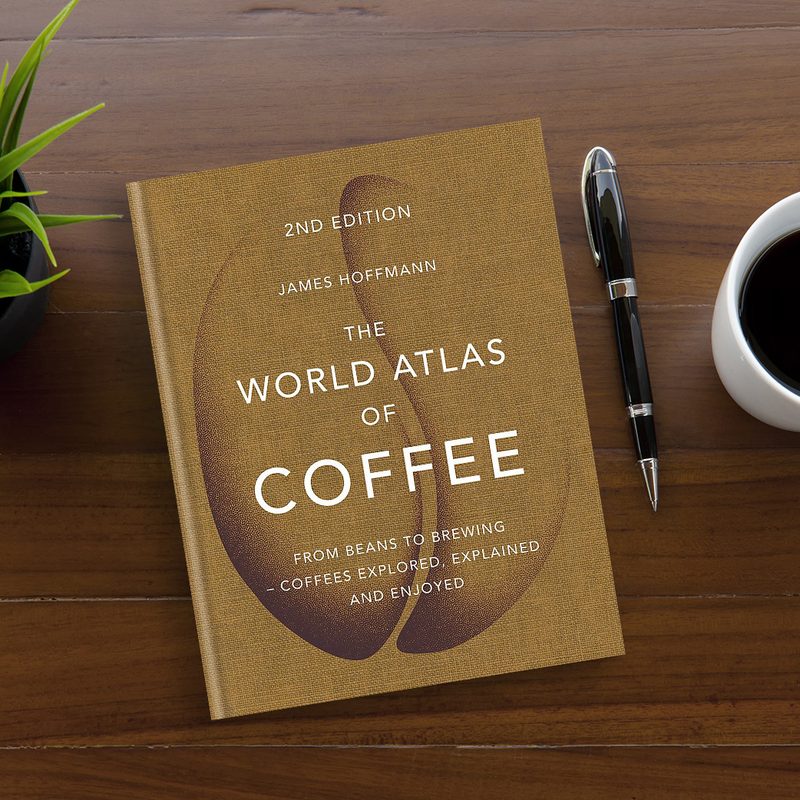 The World Atlas of Coffee by James Hoffman on a wooden table.