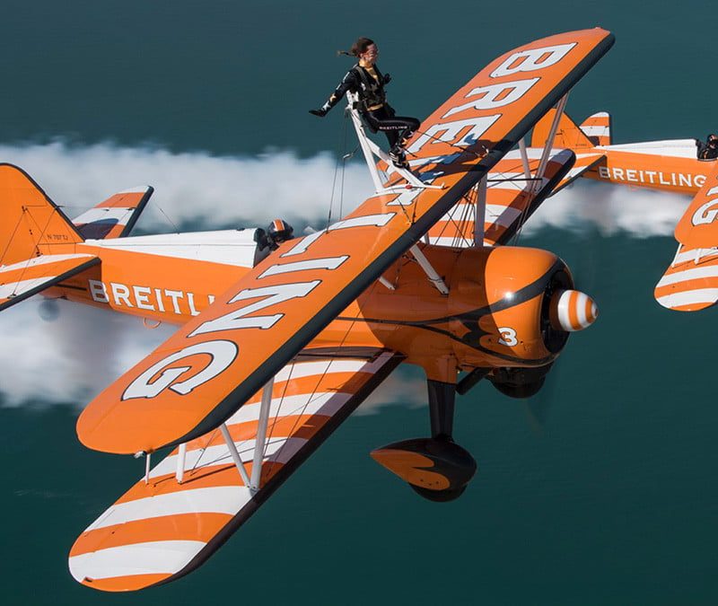 Pair of vintage biplanes with daredevils wing walking on their wings.