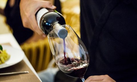 Man pouring red wine in glass during dinner party