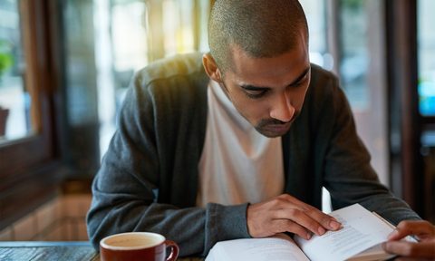 Man reading a book and drinking coffee